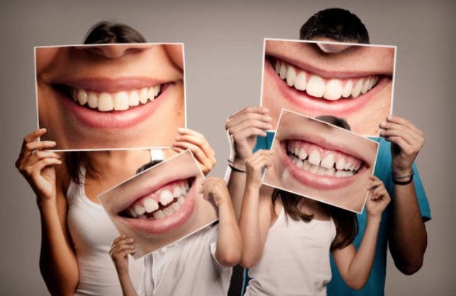 Photo of a family holding up pictures of their smile including teeth
